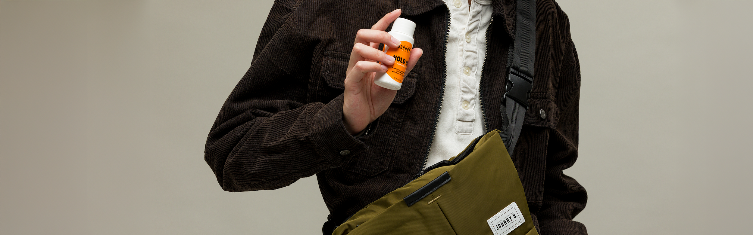 Man pulling out a tube of Utility Cream out of Move Easy crossbody bag 