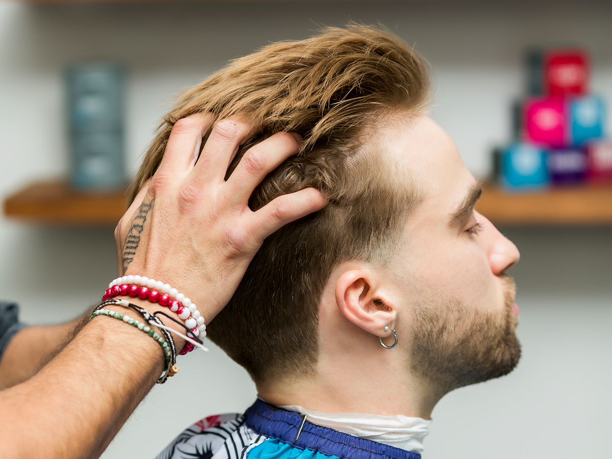 Barber styling client's hair with hands