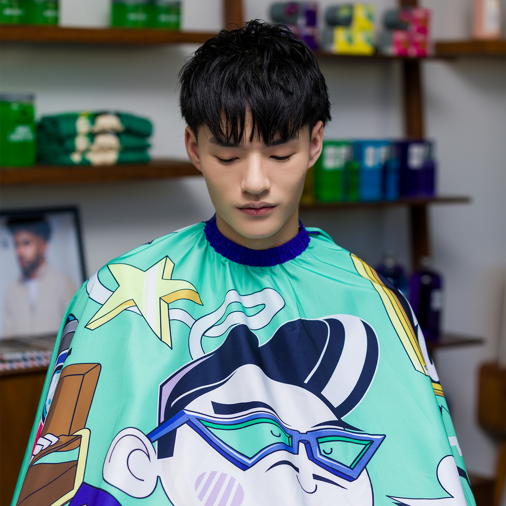 Man wearing Graffiti Cutting Cape in barber chair