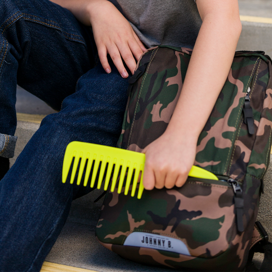 Child putting Juniors Detangle Comb into backpack
