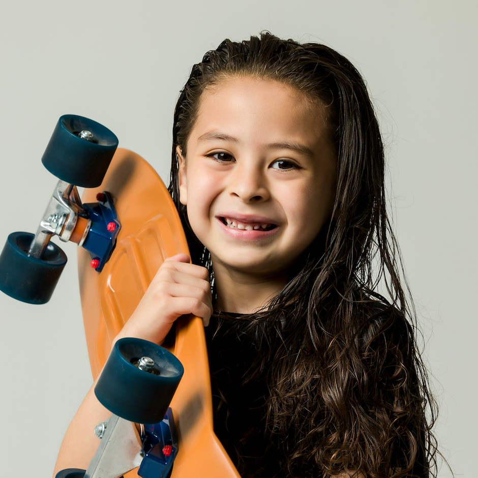 Child holding orange skateboard