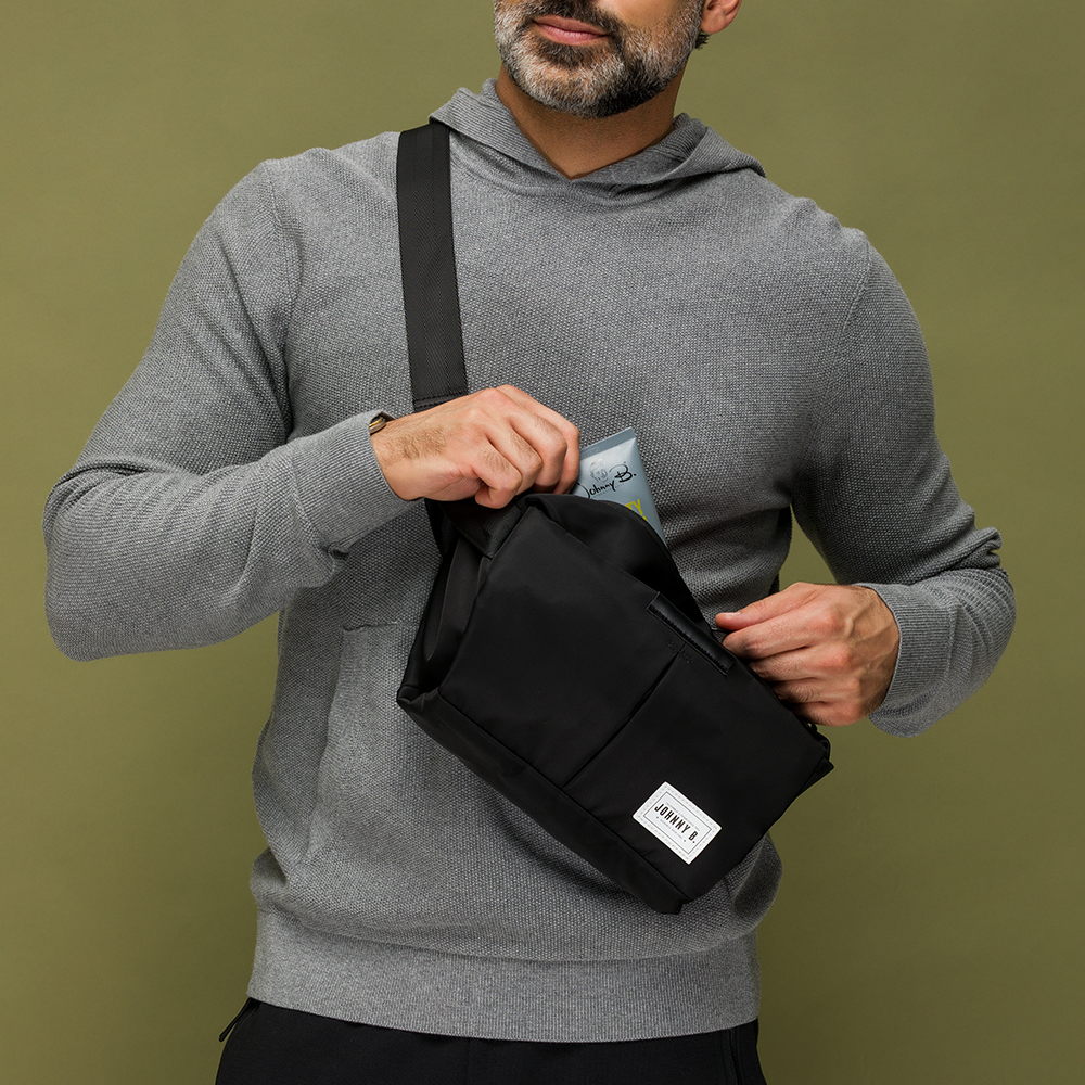 Man pulling out a tube of Utility Cream out of Move Easy crossbody bag