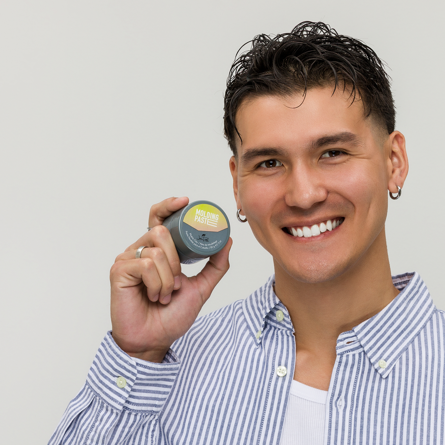 Man holding up a jar of Molding Paste Pomade