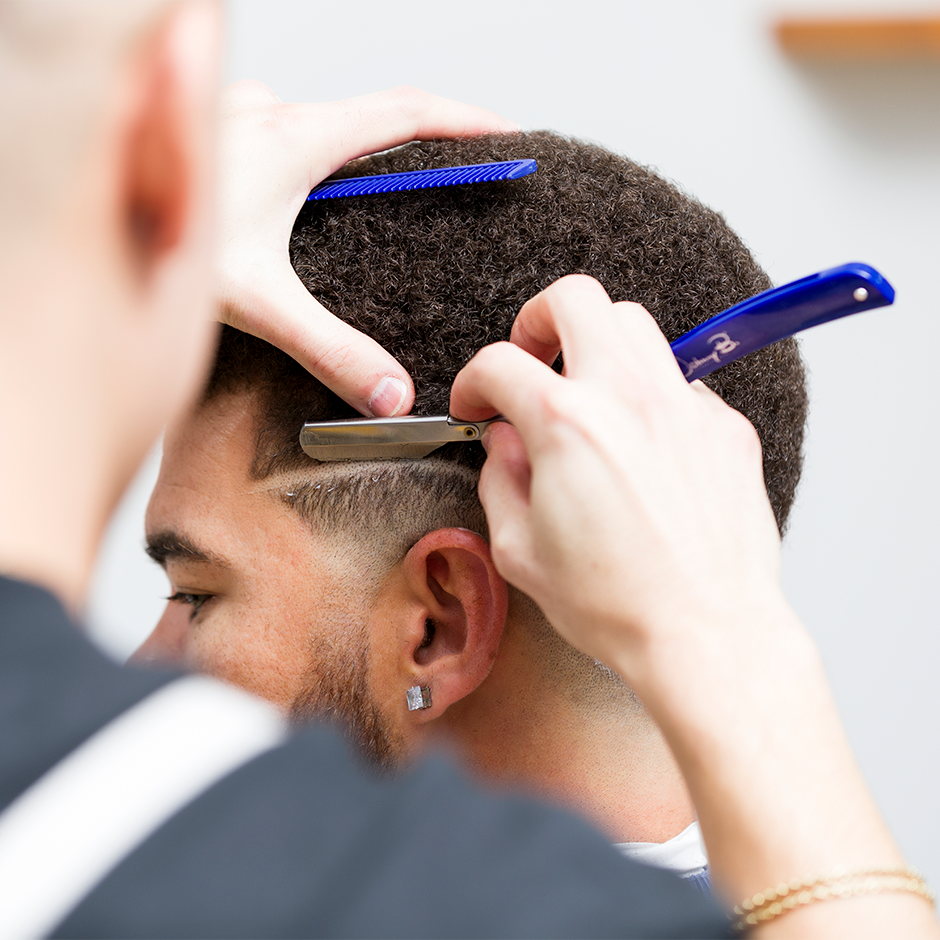 Barber cutting client's hair with Razor